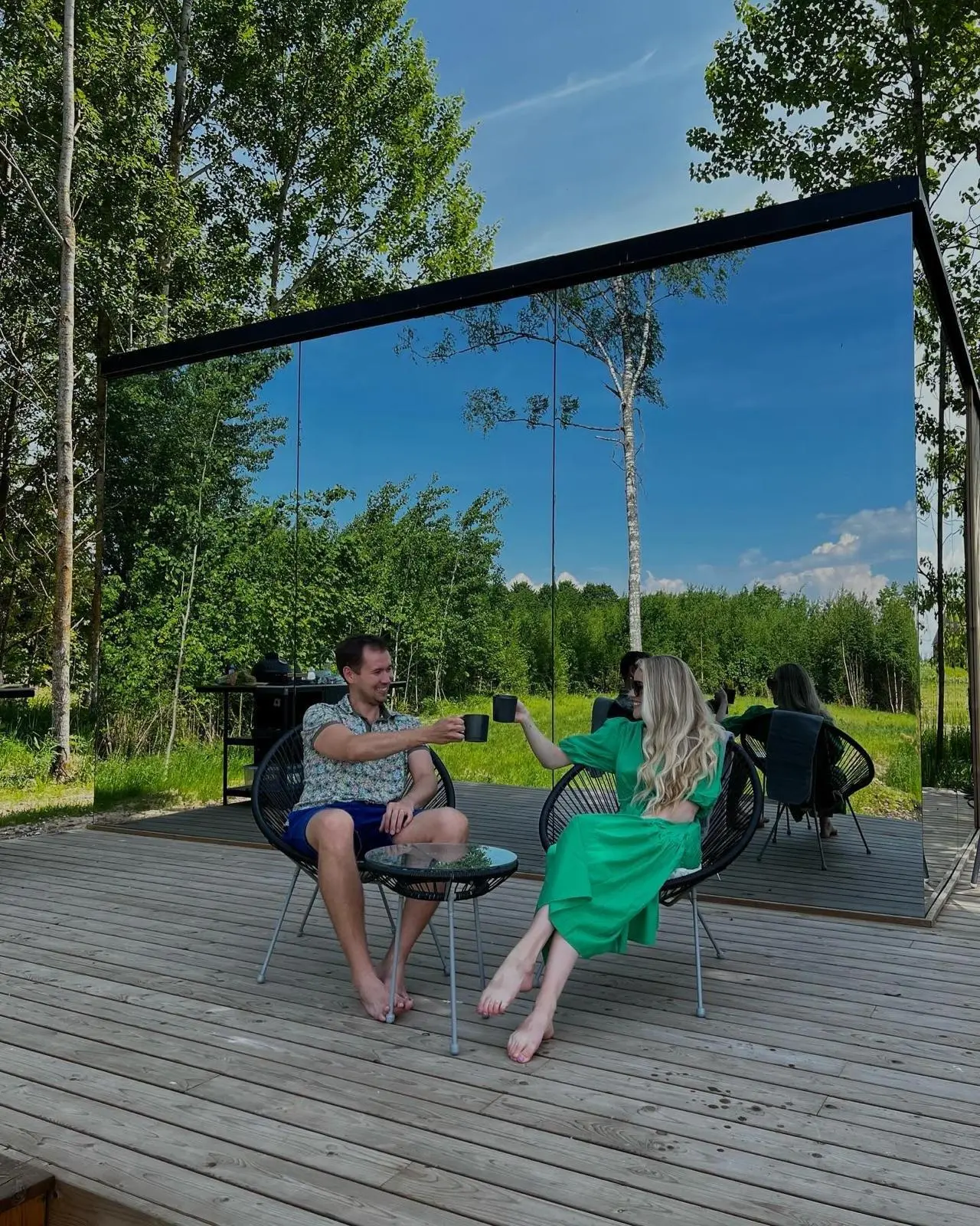 Guests relaxing beside a reflective mirror cabin